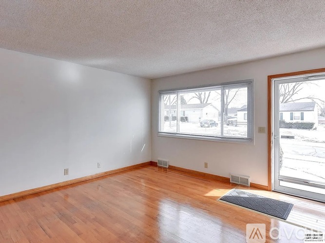 Empty room with a large window and wooden flooring.