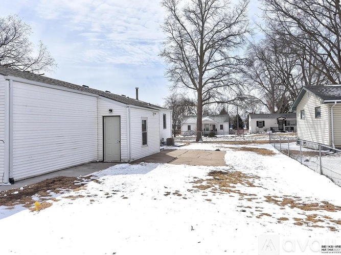 A white building with a grey roof and a white fence in front of it.