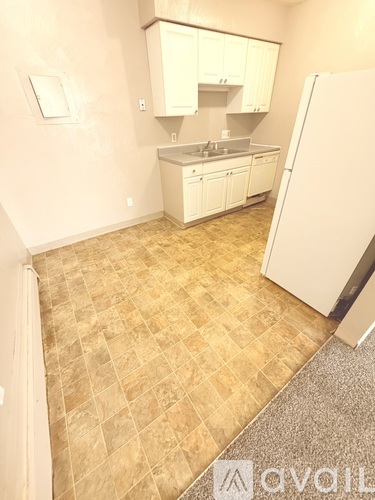 A kitchen with white cabinets and a tiled floor.