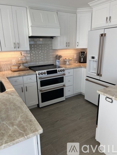 A kitchen with white cabinets and appliances.