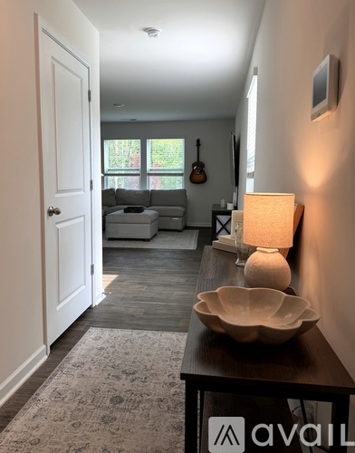 A hallway with a lamp and bowl on a table.