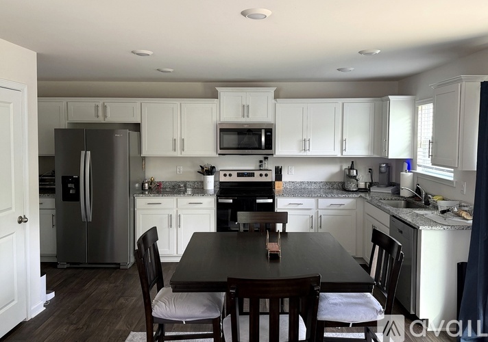 A kitchen with a table and chairs in the foreground.
