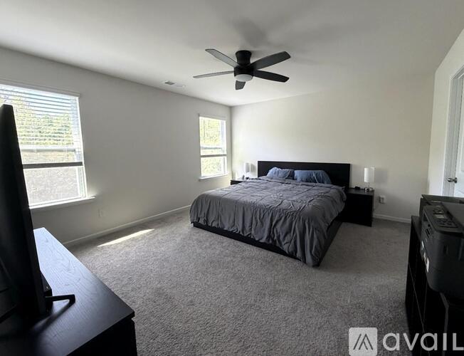 A bedroom with a bed, dresser, and ceiling fan.