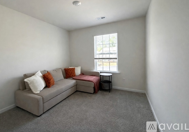A living room with a grey couch and a small table by the window.