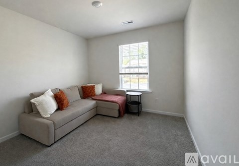 A living room with a grey couch and a small table by the window.