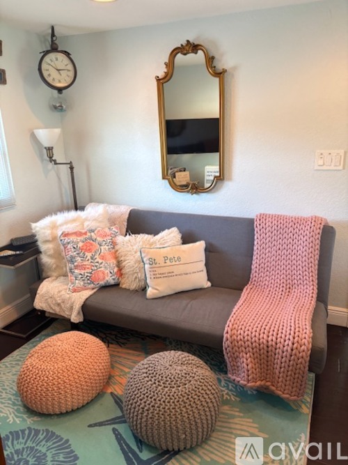A living room with a grey couch, a round orange pillow, a round brown pillow, and a round knitted pillow.