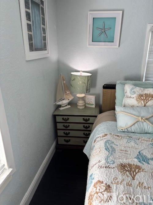 A bedroom with a bed, nightstand, and a picture of a starfish on the wall.