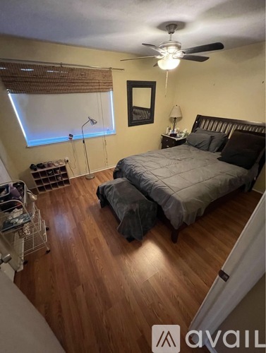 A bedroom with a bed, a ceiling fan, and a window with blinds.