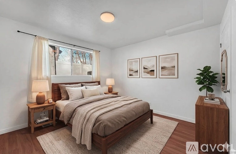 A bedroom with a large bed and a window with curtains.