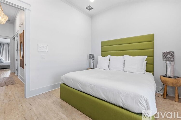 A bedroom with a white bed and green headboard.