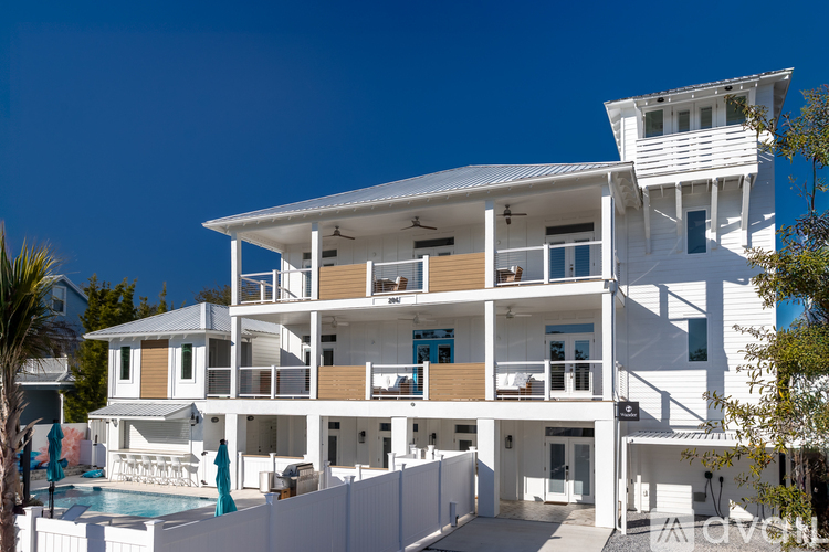 A white multi-story building with a pool in front.