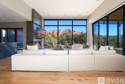 A modern living room with a large white sofa and a view of the mountains outside the windows.