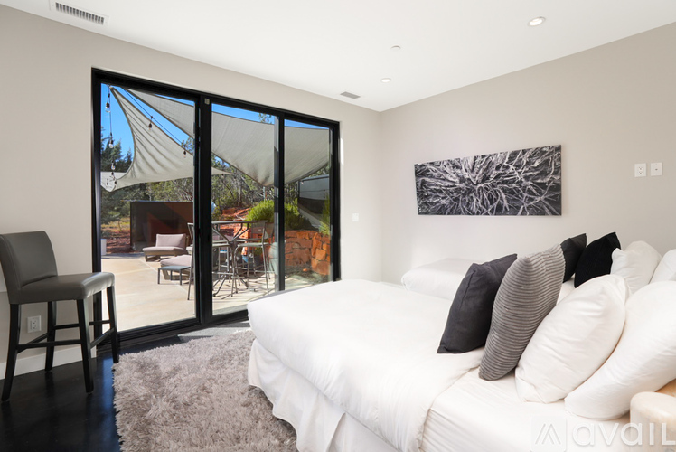 A bedroom with a white bed and a painting on the wall.