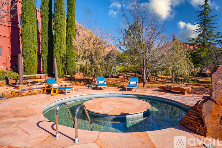 A pool surrounded by trees and chairs.