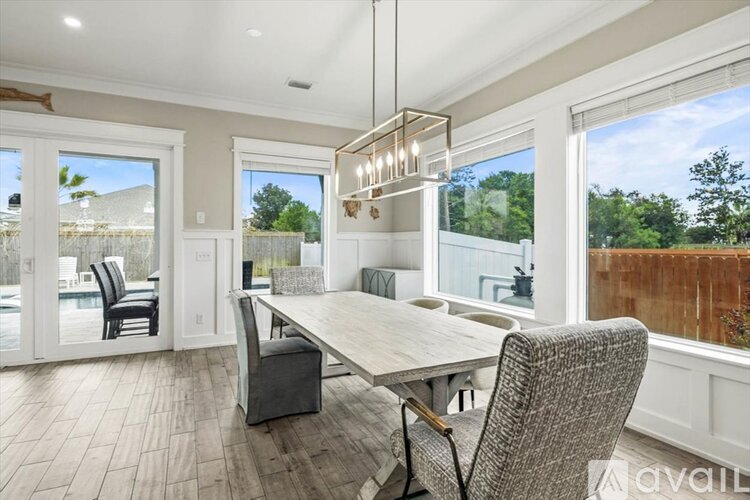 A dining room with a table and chairs and a view of a backyard.