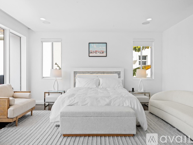 A bedroom with a large bed, a chair, and a nightstand with a lamp.