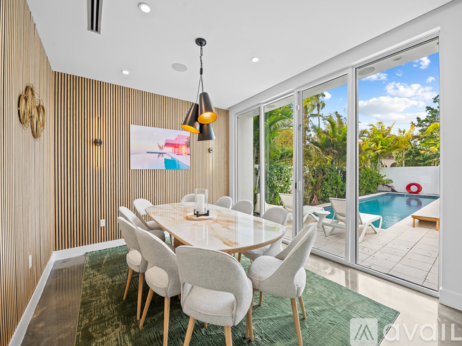 A dining room with a table and chairs and a view of a pool outside.