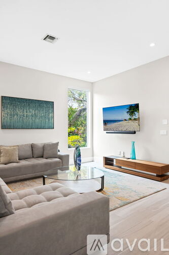 A living room with a grey couch and a painting on the wall.