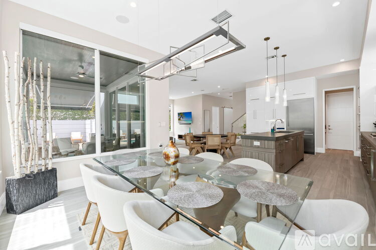A modern dining room with a glass table and white chairs.