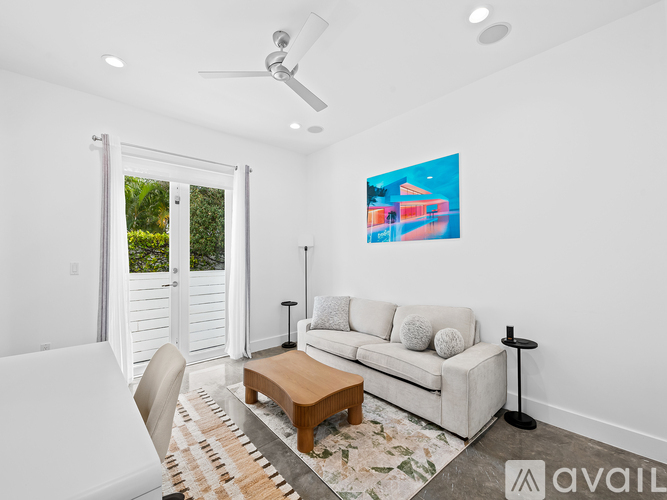 A living room with a white couch, a coffee table, and a painting on the wall.