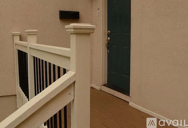 A white railing on a balcony next to a dark green door.