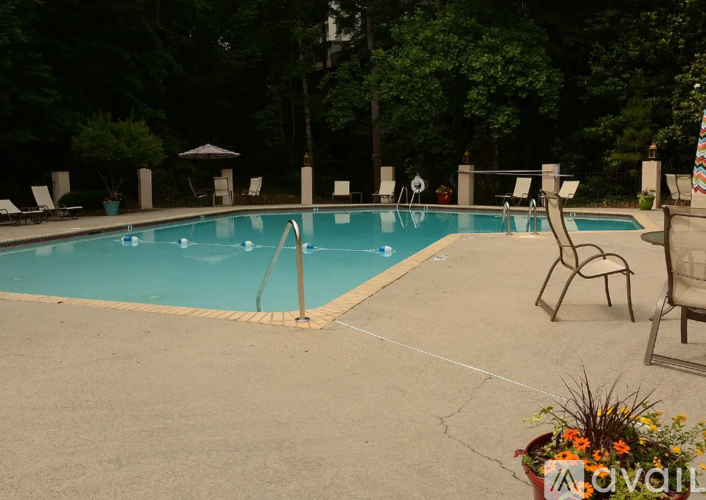 A pool surrounded by chairs and trees.