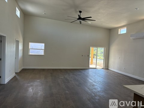 A spacious room with a ceiling fan and a large window.