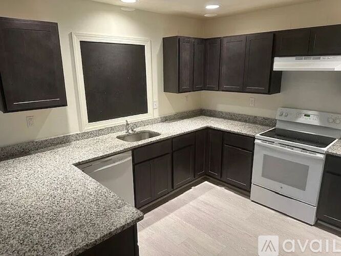 A kitchen with dark brown cabinets and a white stove top oven.