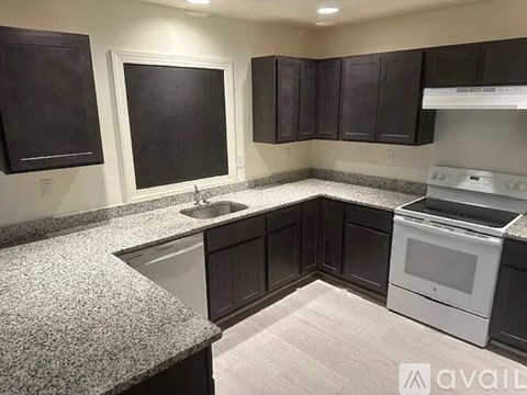 A kitchen with dark brown cabinets and a white stove top oven.