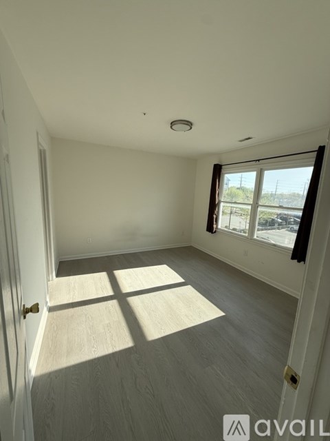 A room with a door, window, and wooden flooring.