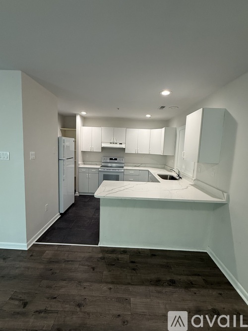 A kitchen with white cabinets and appliances in a room with wooden flooring.