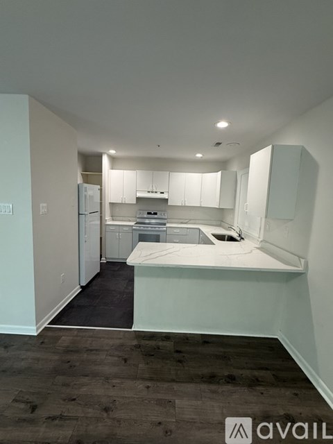 A kitchen with white cabinets and appliances in a room with wooden flooring.