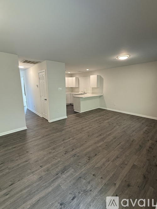 A room with wooden flooring and white walls.