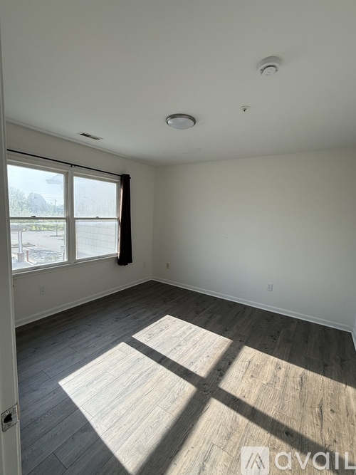 A room with a large window and wooden flooring.