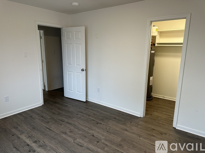A room with a white door and a wooden floor.