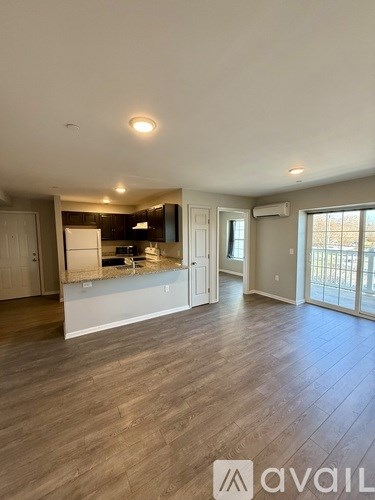 A spacious living room with hardwood floors and a kitchen area in the background.
