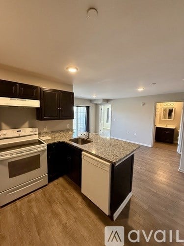 A kitchen with a white stove top oven and black cabinets.