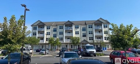 A large apartment building with a parking lot in front of it.