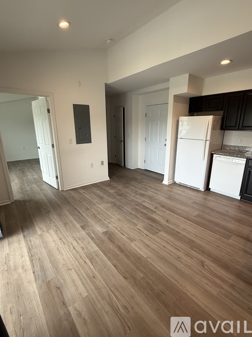 A spacious kitchen with white appliances and wooden flooring.