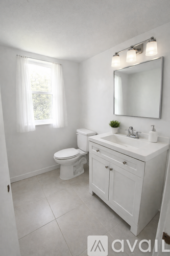 A white bathroom with a toilet, sink, and mirror.