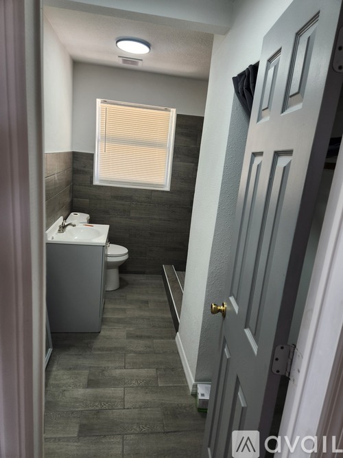 A bathroom with a toilet, sink, and a window with blinds.