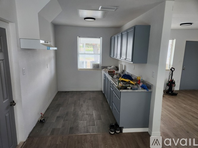 A kitchen with grey cabinets and a grey floor.