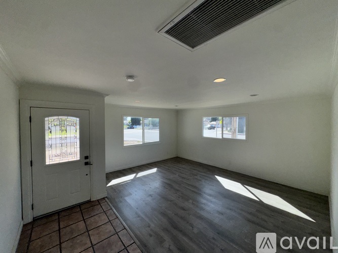 A spacious room with wooden flooring and a door leading to a balcony.
