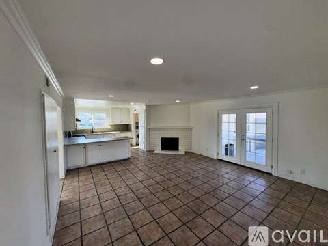 A living room with a fireplace and a kitchen in the background.