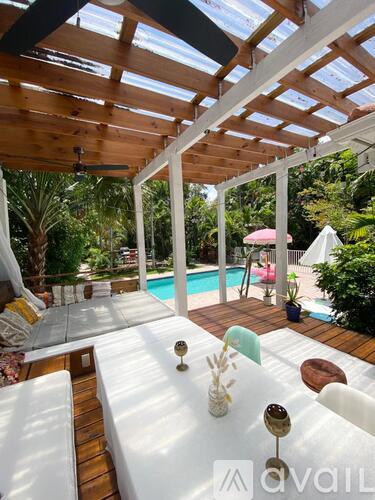 A wooden deck with a glass roof overlooking a pool.