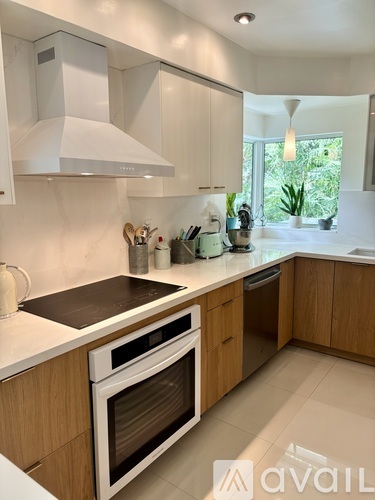 A modern kitchen with wooden cabinets and a white range hood.