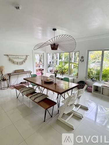 A dining room with a wooden table and white chairs.