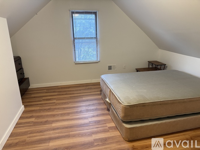 A bedroom with a bed, dresser, and window.