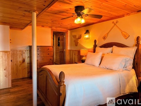 A bedroom with a bed, a ceiling fan, and a wooden wall.