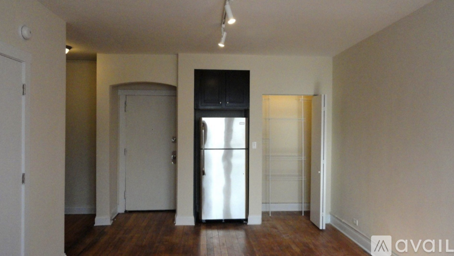 A bedroom with a bed, a table, and a refrigerator.